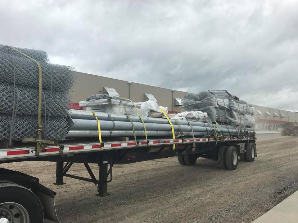 Photo of a flatbed truck full of chain link fence materials ready for installation